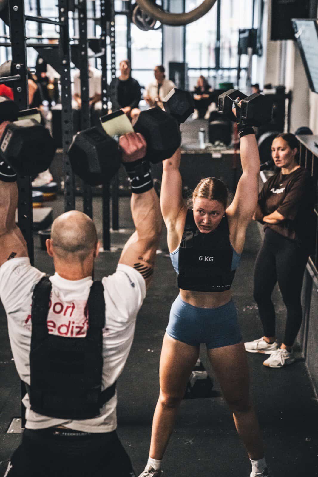 Coach korrigiert Dumbbell Overhead